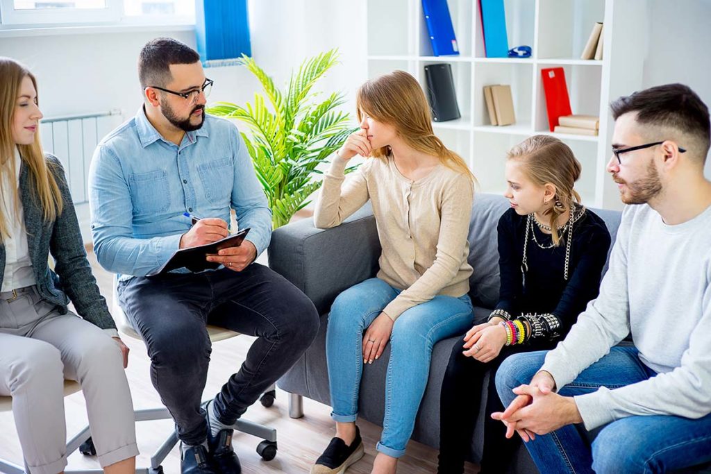 family members on couch talk with a therapist and experience family therapy benefits