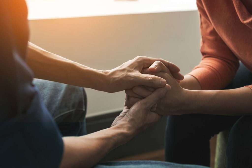 person holding another person's hands while discussing what does psychotherapy do