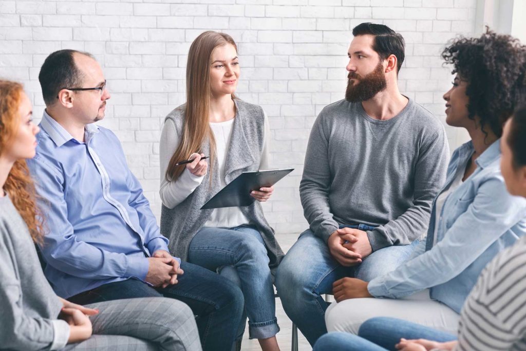 people in a circle discuss the stages of group therapy