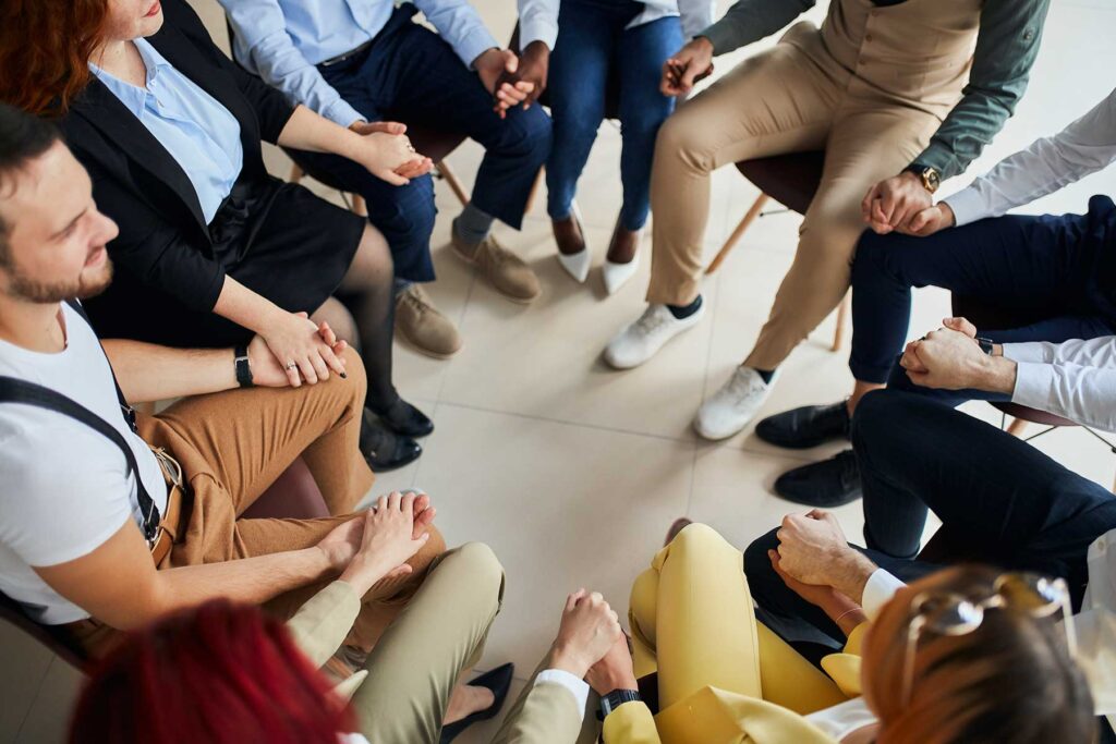 people sitting in a circle discuss group therapy activities for adults
