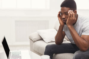 man with head in hands sitting on couch considers starting an anxiety treatment program