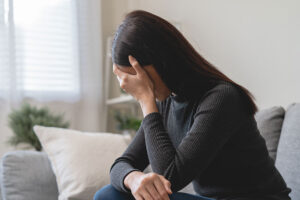 woman on couch with head in hands considers depression treatment