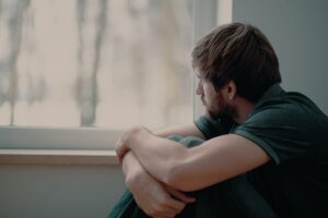 person pulling knees into chest while sitting and looking out window and wondering how to get off fentanyl