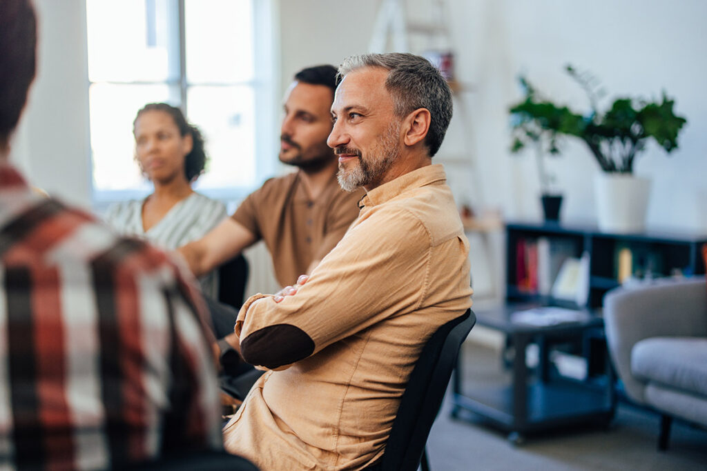 smiling person in group therapy learning the importance of a continuing care program