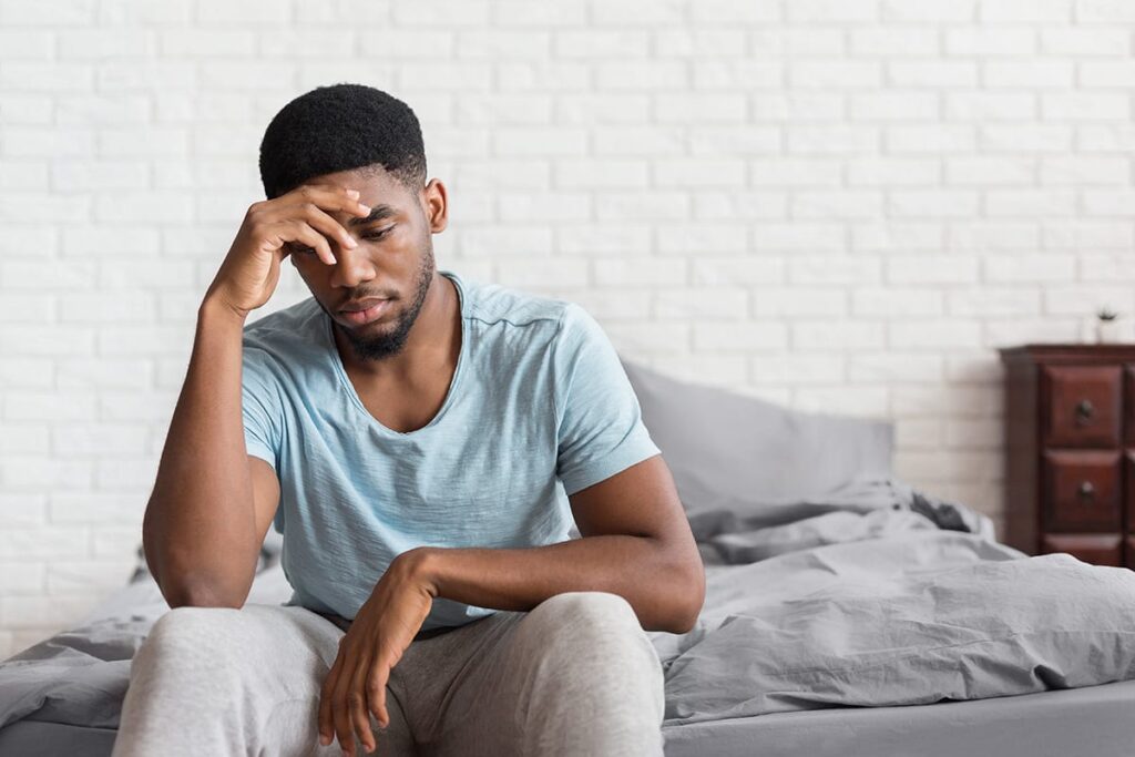 person sitting on couch suffering with headache while experiencing symptoms of wet brain