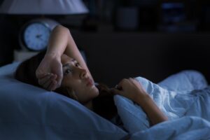 person lying in bed in the dark while experiencing opioid withdrawal insomnia